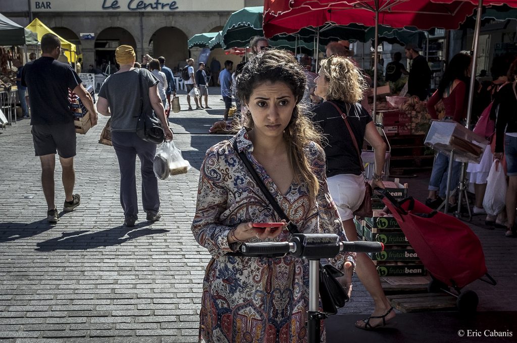 Au marché de plein air de Revel une jeune femme vient de consulter son téléphone Photojournalisme Streetphotography Eric Cabanis
