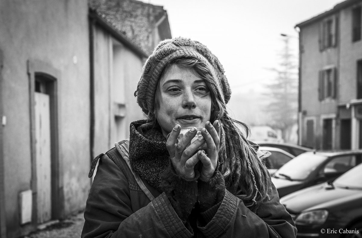 Elodie, une jeune marginale d'origine belge, boit un café à la terrasse d'un café de Couiza dans la haute vallée de l'Aude avant d'aller au marché de Espéraza, le 2 février 2020 Photojournalism Streetphotography Portrait Eric Cabanis