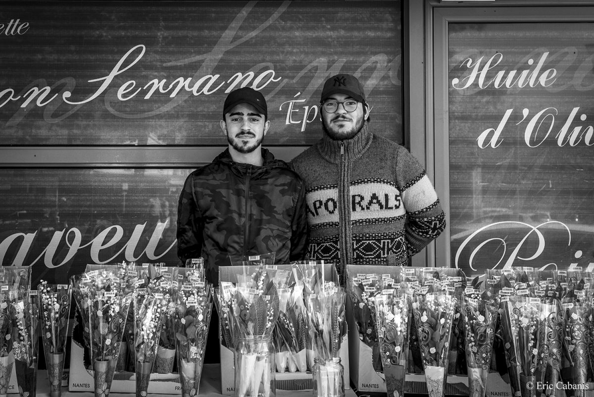 Deux jeunes hommes posent devant leur étal de muguet qu'ils vendent à l'occasion du 1er mai 2019 à Toulouse Two young men pose in front of their lily of the valley stall on 1 May 2019 in Toulouse Photojournalism Streetphotography Eric Cabanis